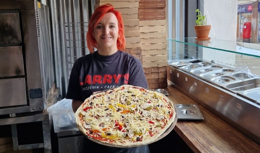 Owner Mary holding fresh pizza