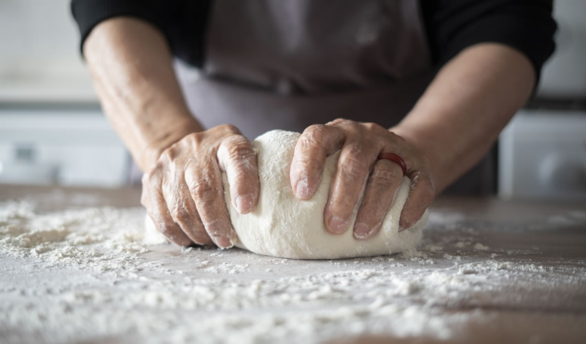 Close-up hands kneading pizza dough