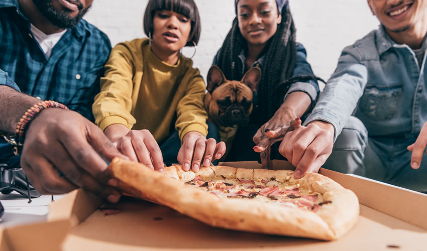 Group of people reaching for takeaway pizza