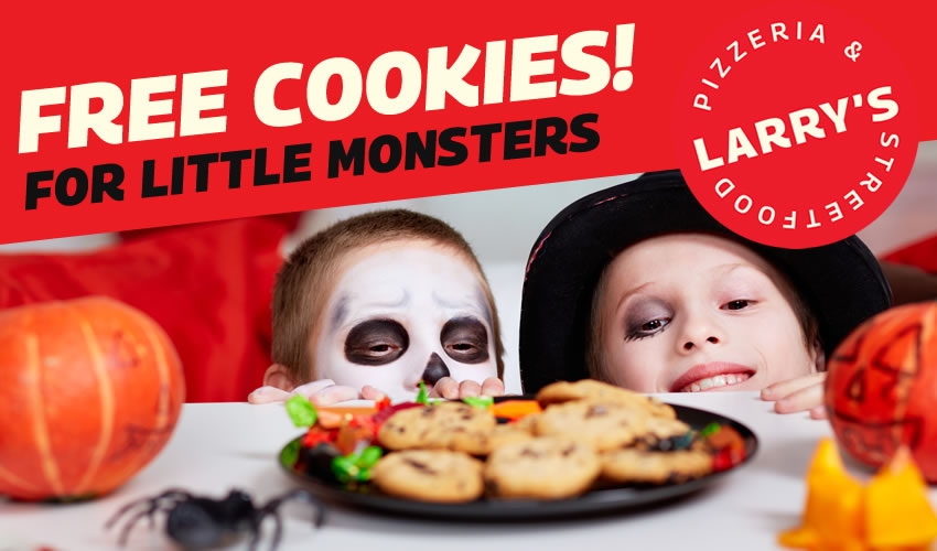 Children dressed up for halloween looking over a table at cookies